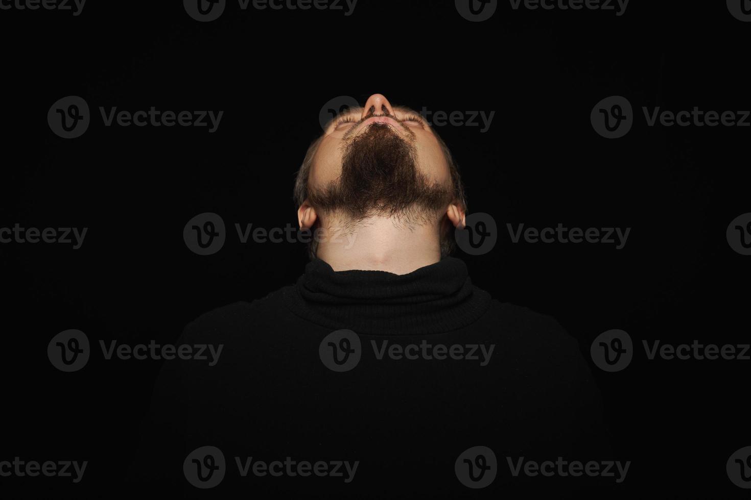 Cute bearded man, threw head back, black background photo