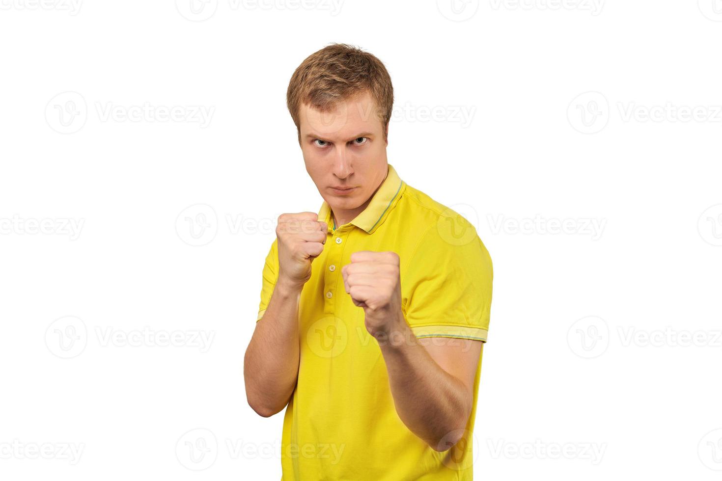 Angry young man in yellow T-shirt ready to fight with fists isolated on white background photo