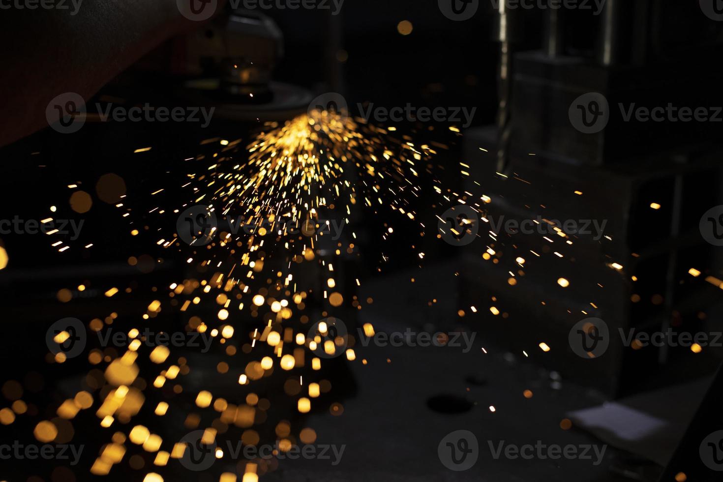Metal treatment. Grinding of steel. Sparks from disk. Work in workshop. photo