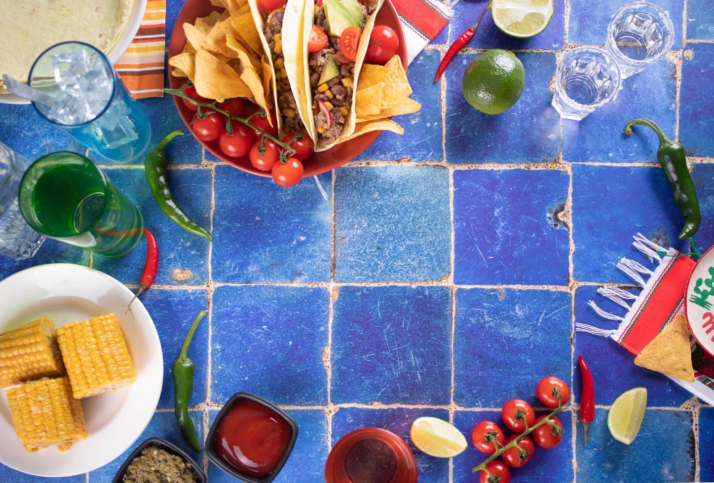 Traditional Mexican corn tacos with meat, vegetables, avocado, beans, salsa and nachos. Served with various sauces and drinks. Top view. Big family gatherings. photo