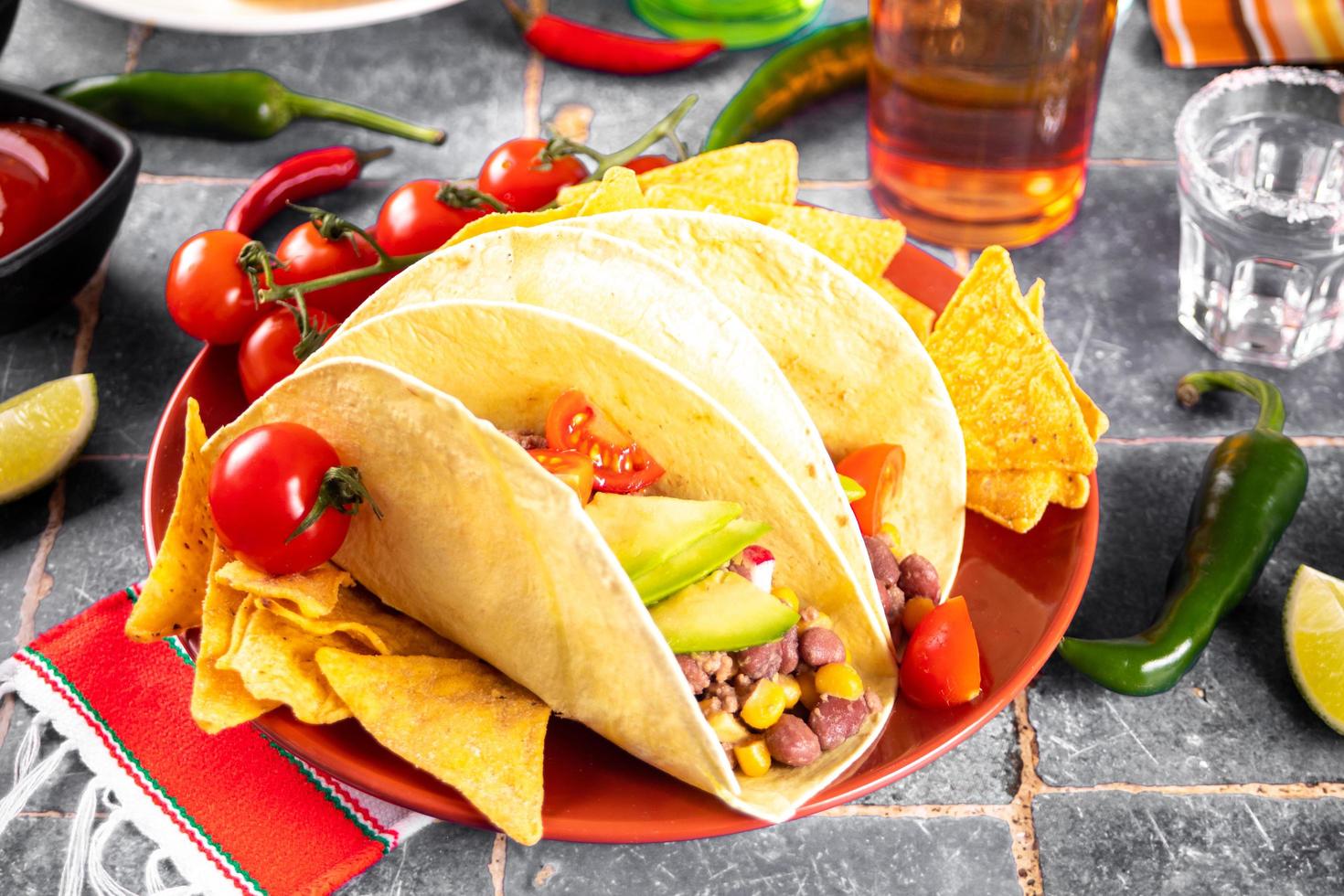 Traditional Mexican corn tacos with meat, vegetables, avocado, beans, salsa and nachos. Served with various sauces and drinks. Top view. Big family gatherings. photo