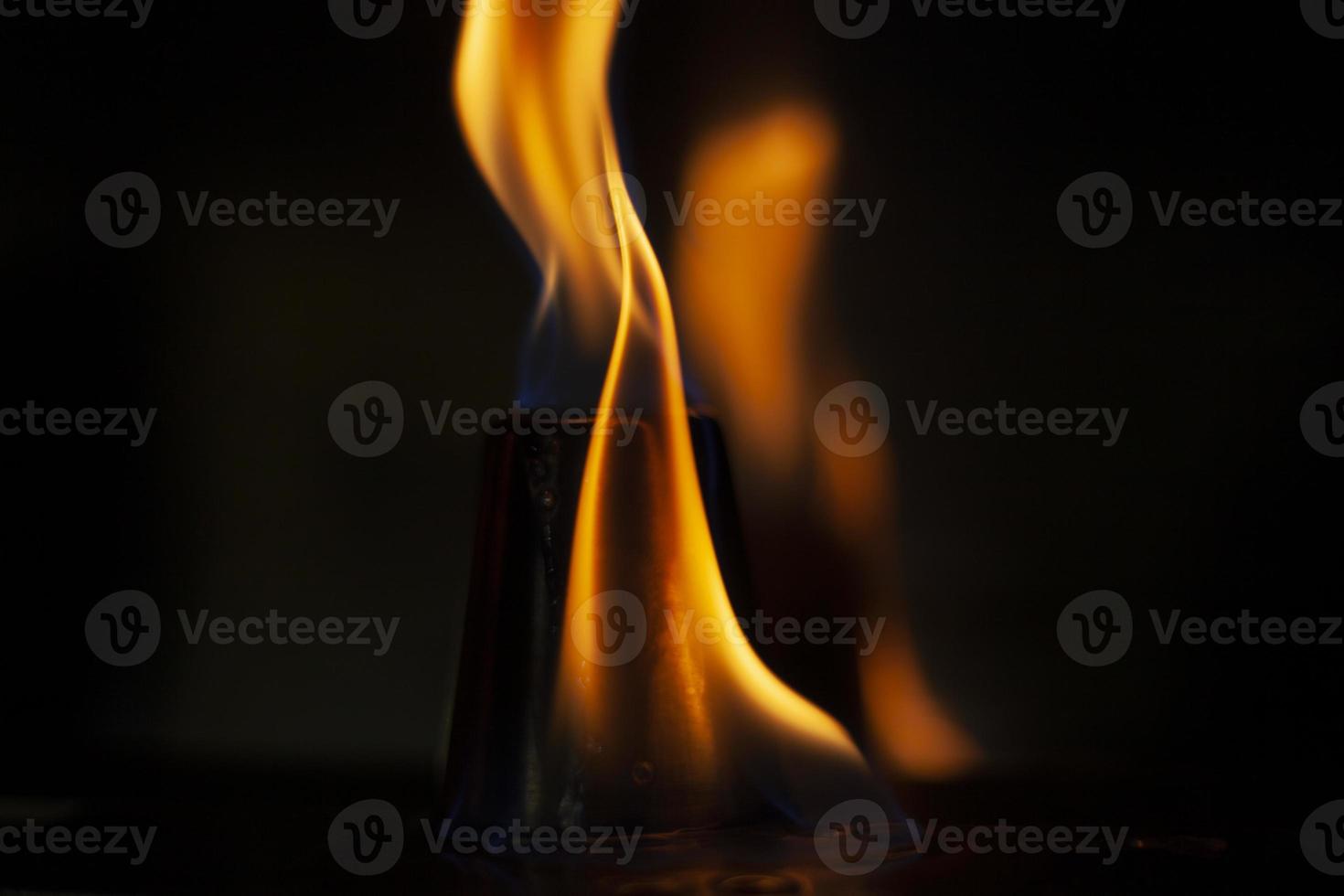 Flames in dark. One flame on black background. Ignition details. Fire burns yellow. photo