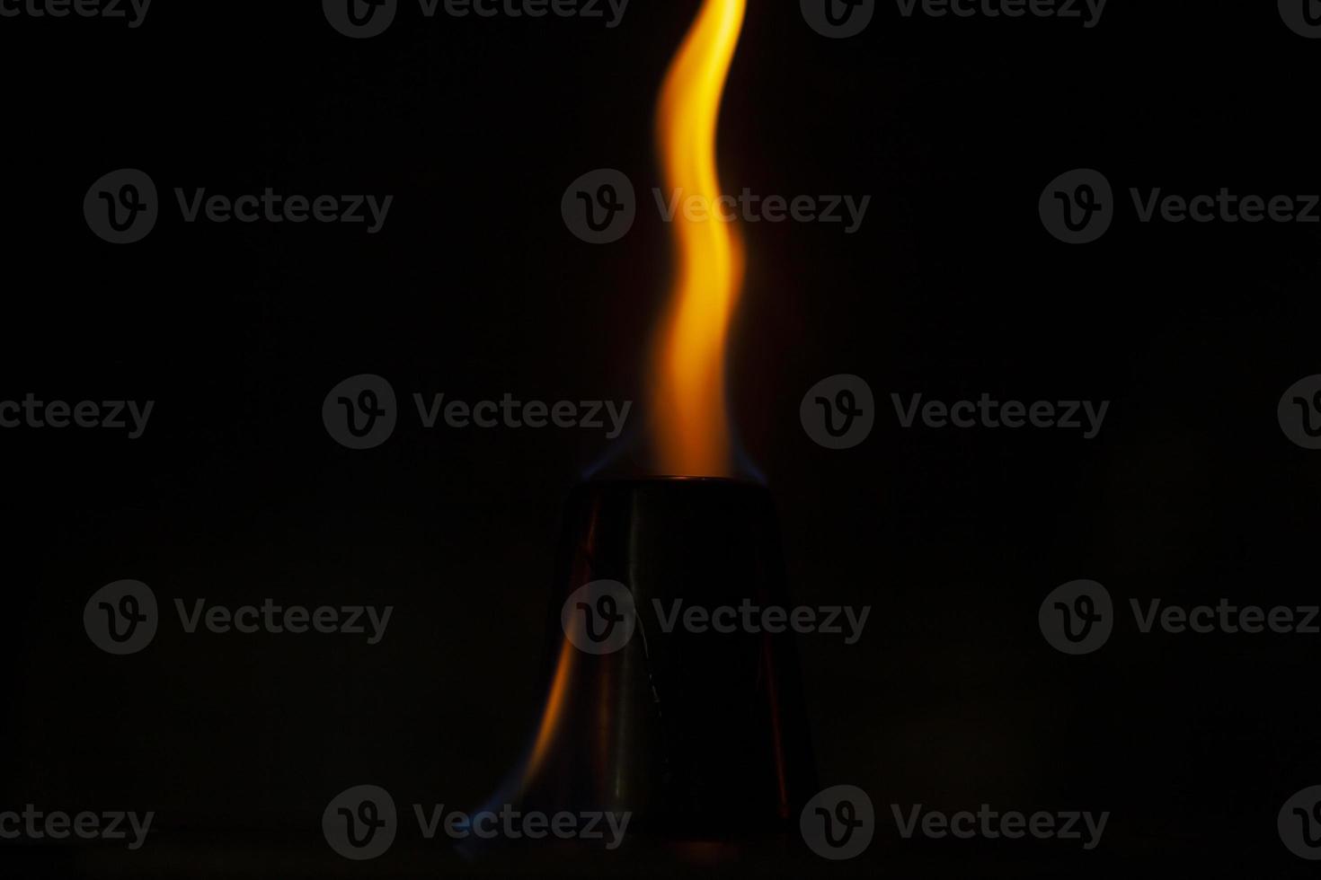 Flames in dark. One flame on black background. Ignition details. Fire burns yellow. photo