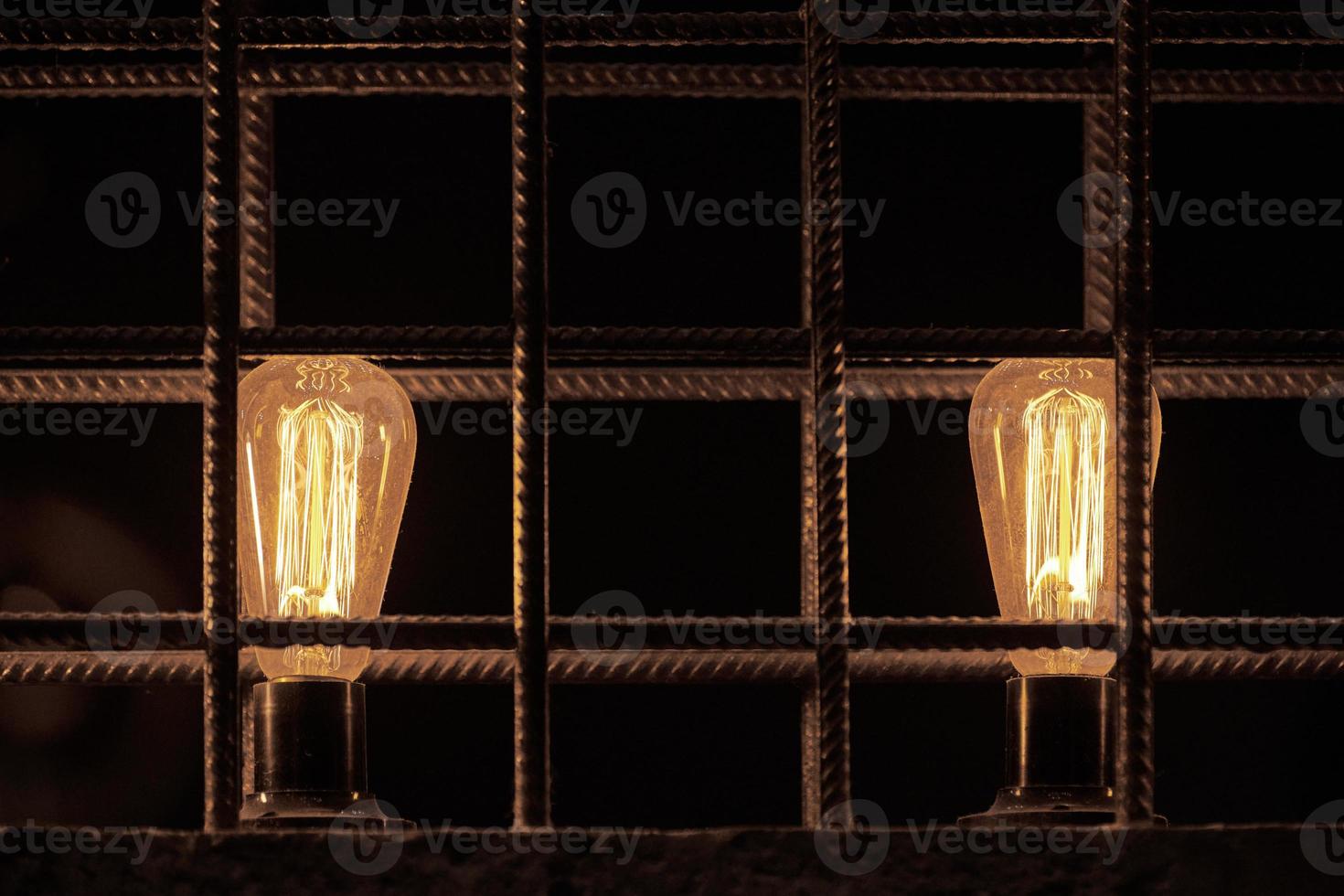 Two decorative incandescent light bulbs inside loft partition from reinforced steel bar photo