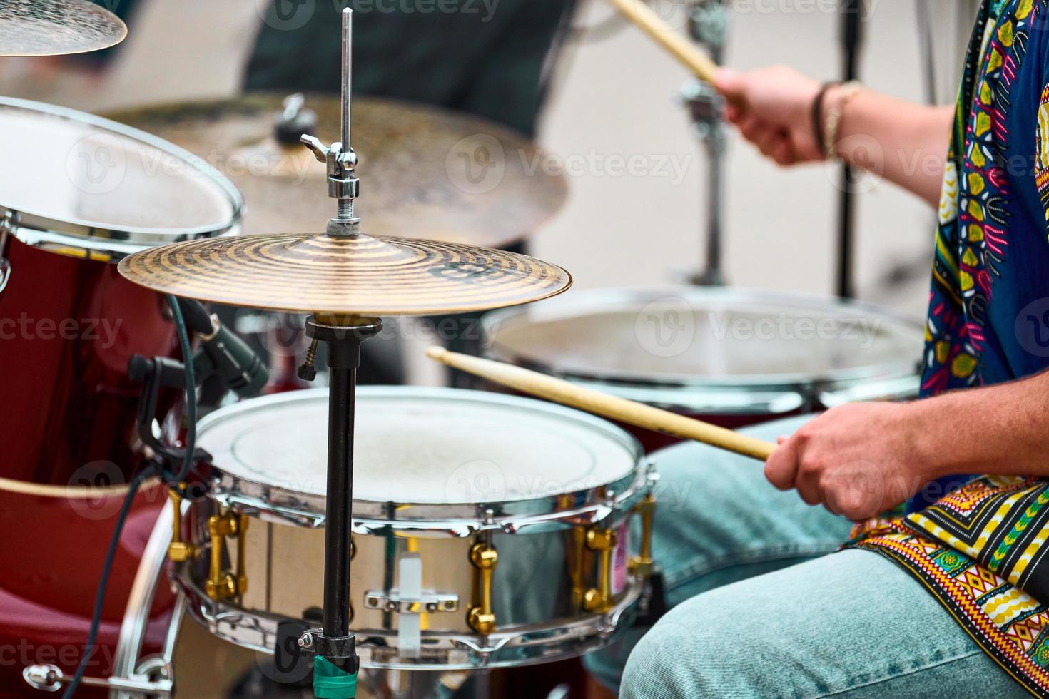 Drummer man playing drums percussion with drum sticks, drum set on concert stage, sticks and drums photo