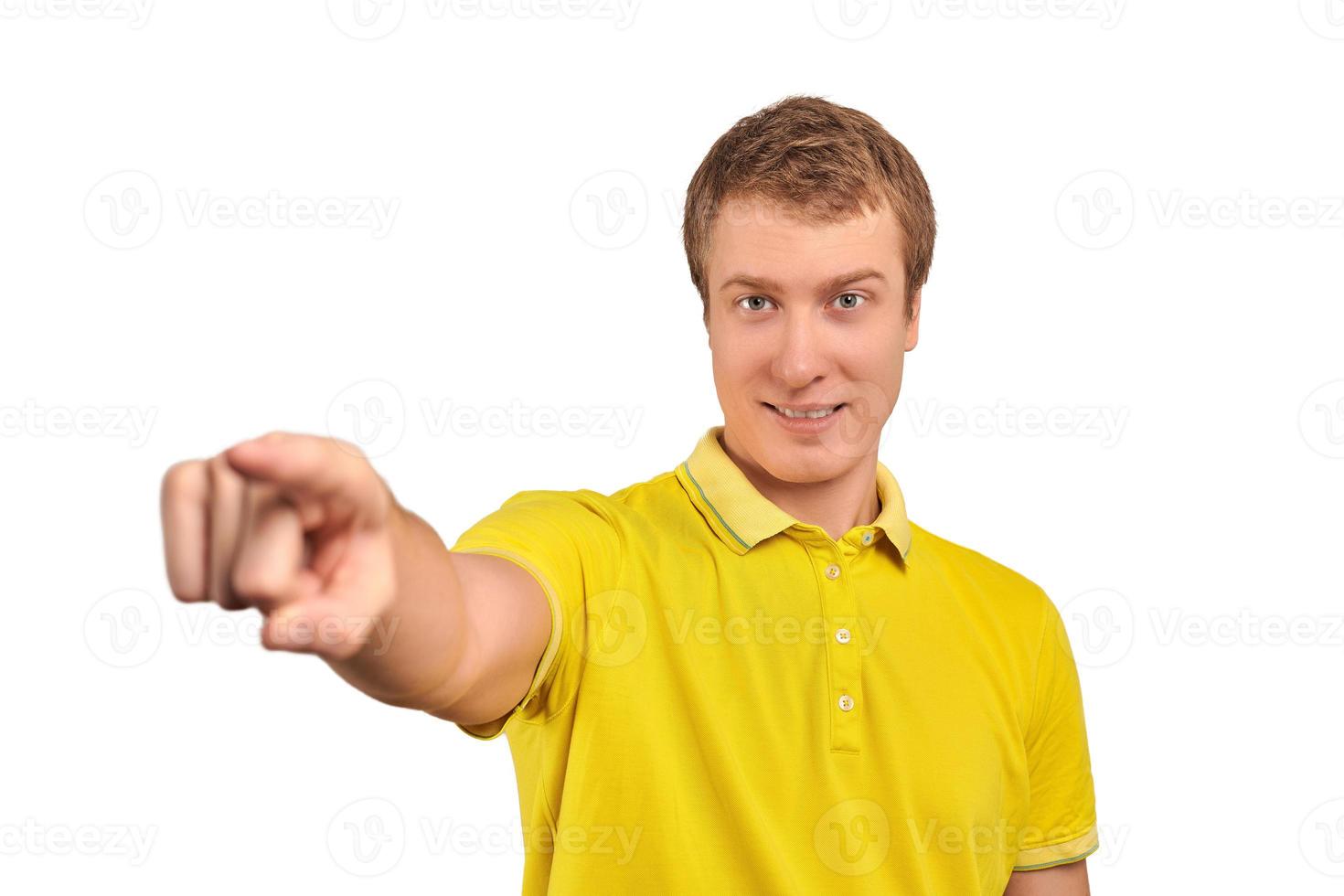 Smiling attractive handsome guy in casual yellow T-shirt pointing forward, isolated white background photo