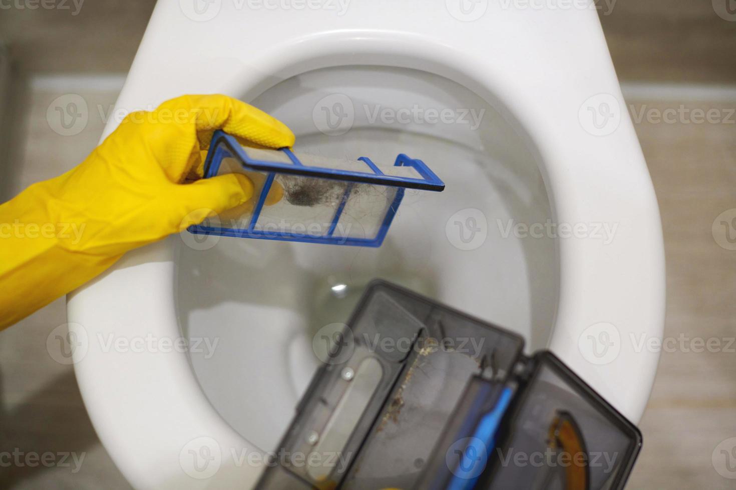 Hands in rubber gloves throw out trash in toilet, close up. photo