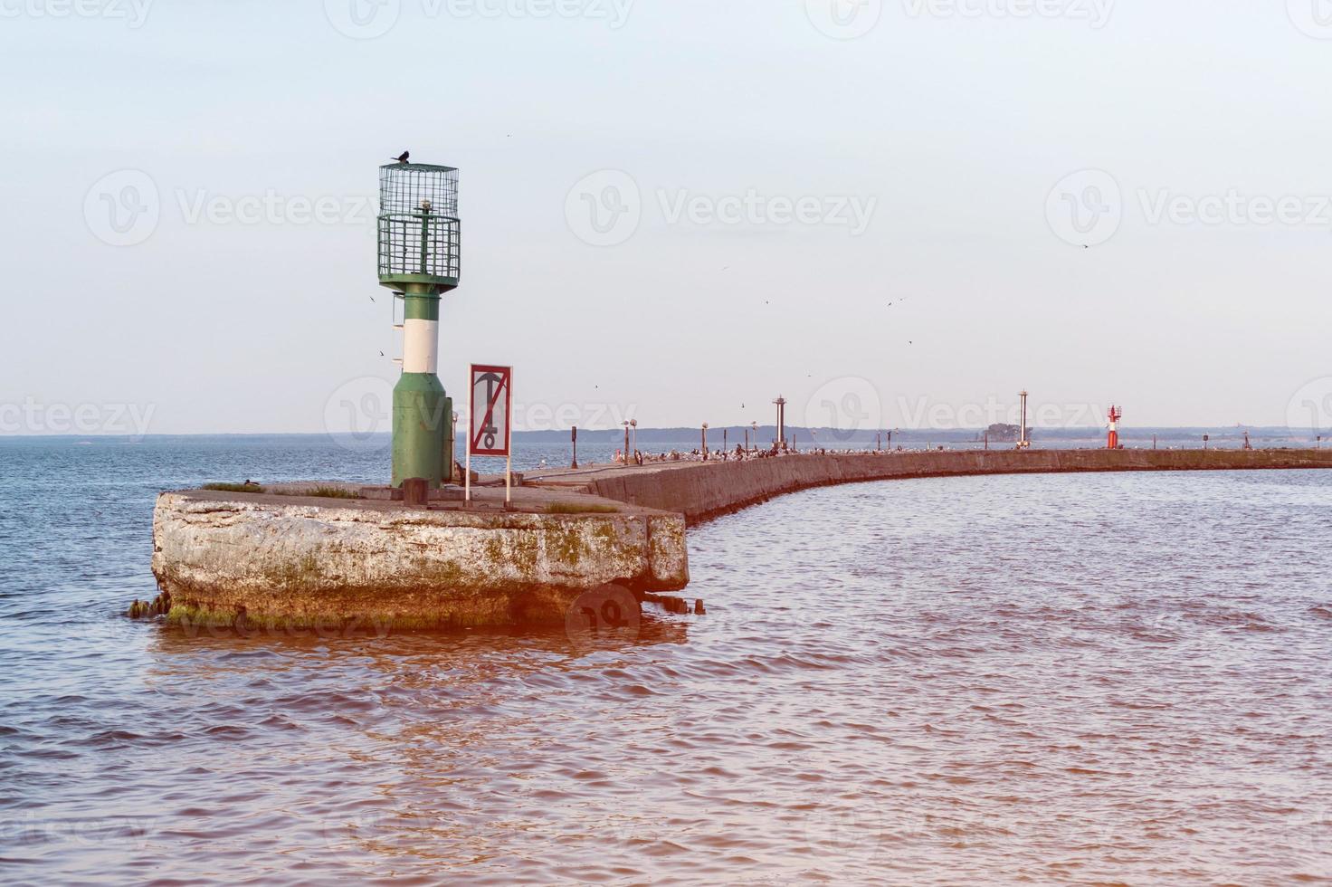 Jetty near seaport with modern lighthouse buoys. Beautiful seascape, copy space. Breakwater for protect ships at shipyard from waves photo