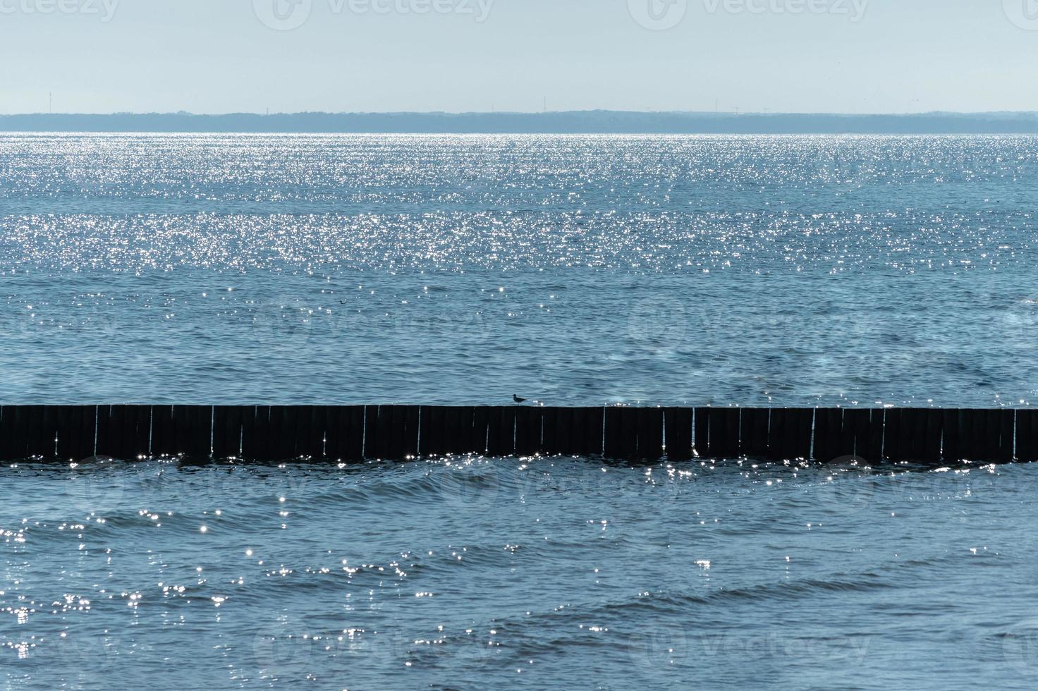 Breakwater on beach. Wooden sea separator. Beautiful seascape. Protection holidaymakers from effects of both weather and longshore drift. photo