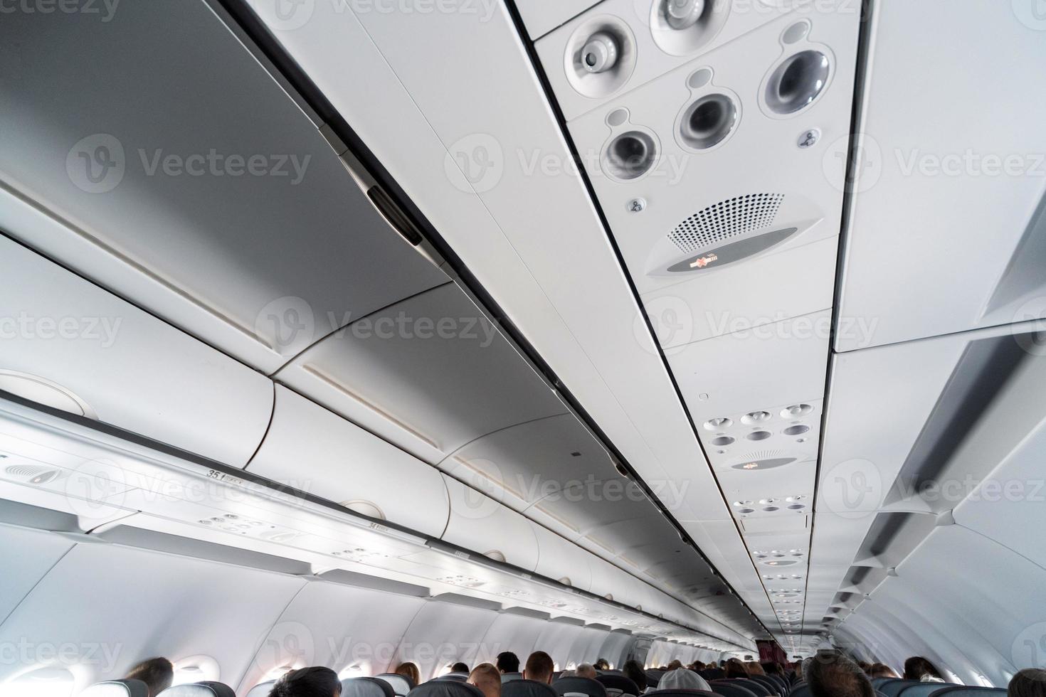 Airplane air conditioning control panel over seats. Stuffy air in aircraft cabin with people. New low-cost airline. photo