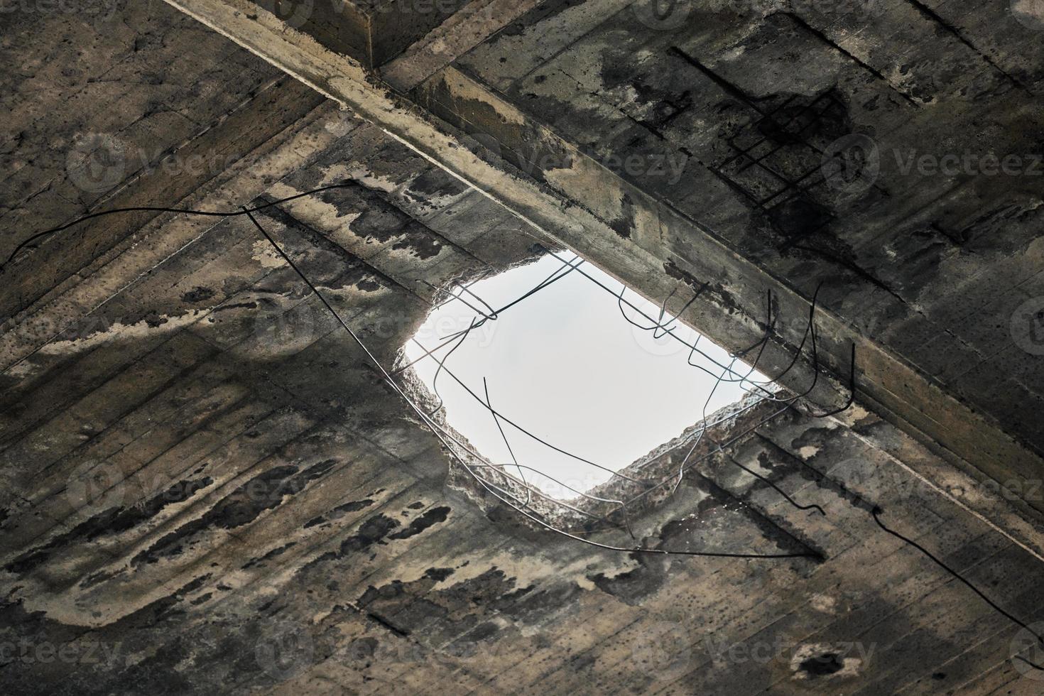 Abandoned damaged roof with hole in ceiling overlooking cloudy sky, close up photo