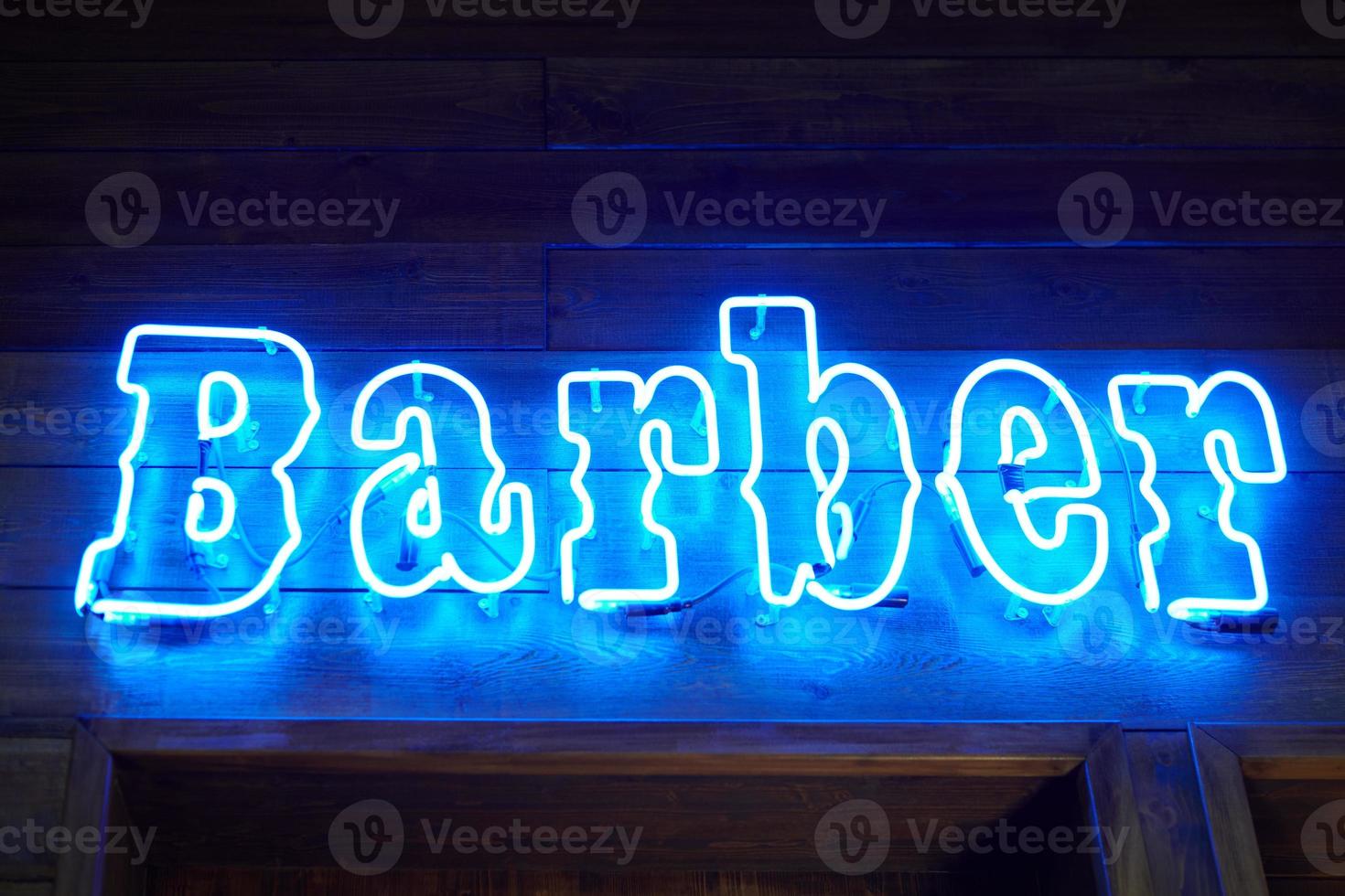 canto de pared de neón azul con inscripción de barbero brillante en el interior de la barbería de loft, tira de luz foto