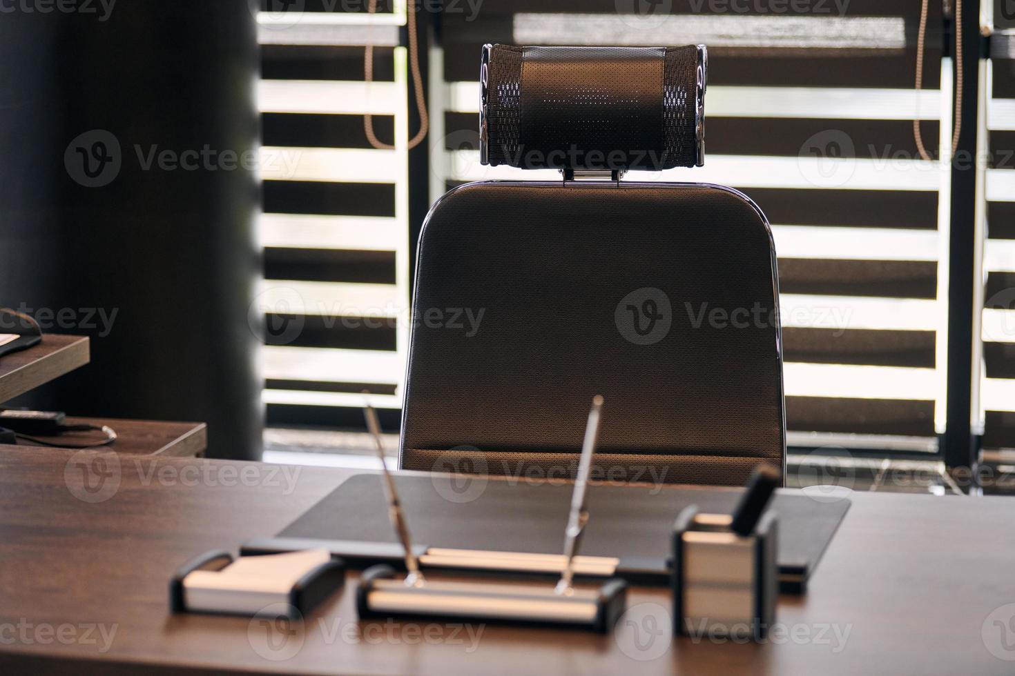 lugar de trabajo de la oficina de negocios. lugar de trabajo para jefe, jefe u otros empleados. mesa y silla cómoda. luz a través de las persianas entreabiertas foto