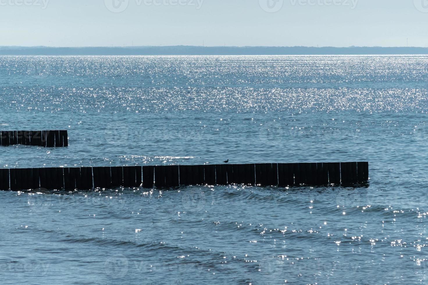 Breakwater on beach. Wooden sea separator. Beautiful seascape. Protection holidaymakers from effects of both weather and longshore drift. photo