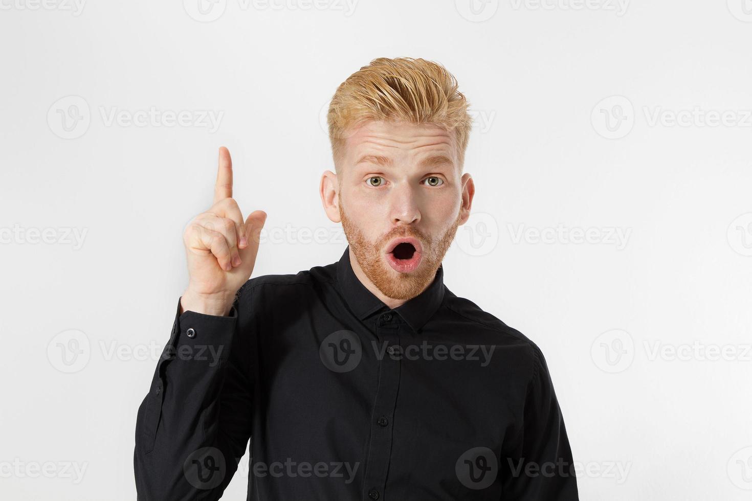 Young man has an idea pointing to copy space . Close up redheaded guy with red beard isolated. Shock happy excited male face. Education knowledge concept. Idea creator. Optimist person idea-generating photo
