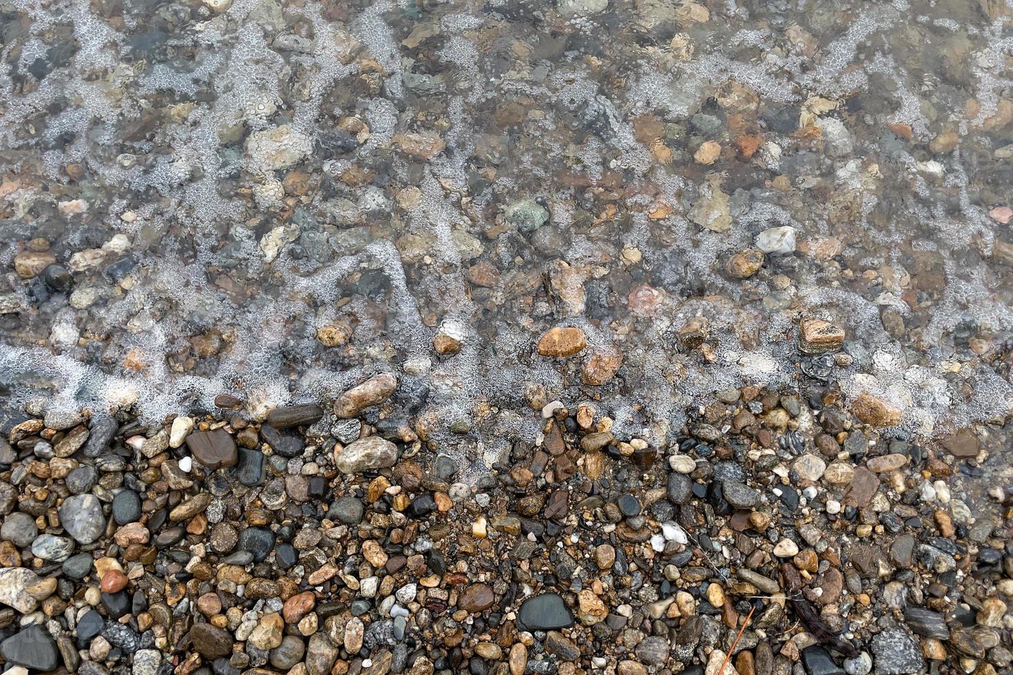 textura de agua y guijarros en la orilla foto