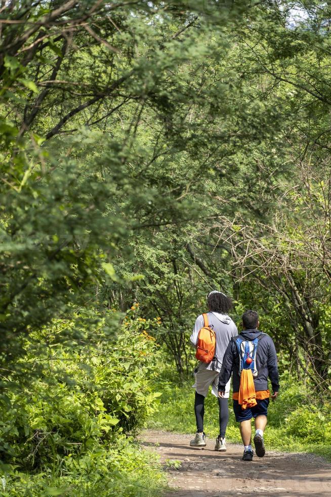 two young men and friends descending in the ravine, vegetation and trees, huentitan ravine guadalajara, mexico photo