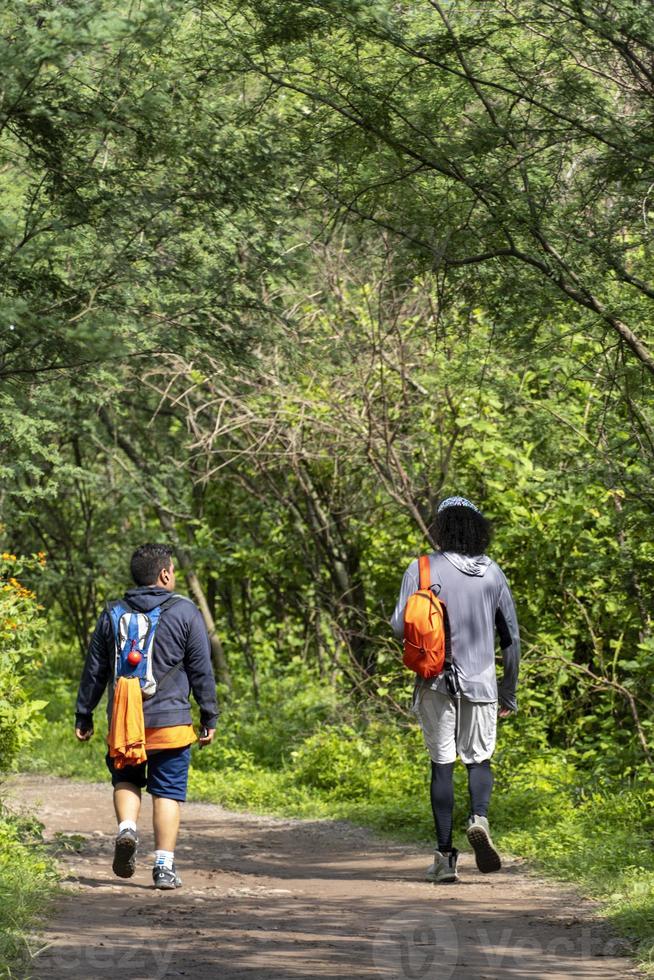 two young men and friends descending in the ravine, vegetation and trees, huentitan ravine guadalajara, mexico photo