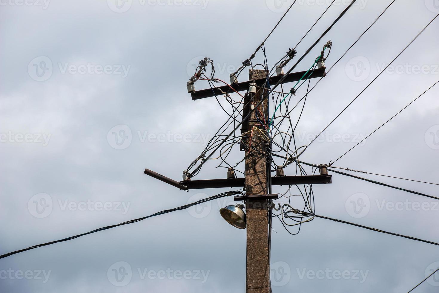 Electric pole power lines outgoing electric wires againts on cloud blue sky. photo