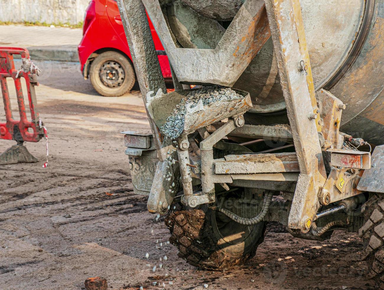 Mobile concrete mixer at the construction site. Close-up of gravel being loaded into a concrete making machine photo