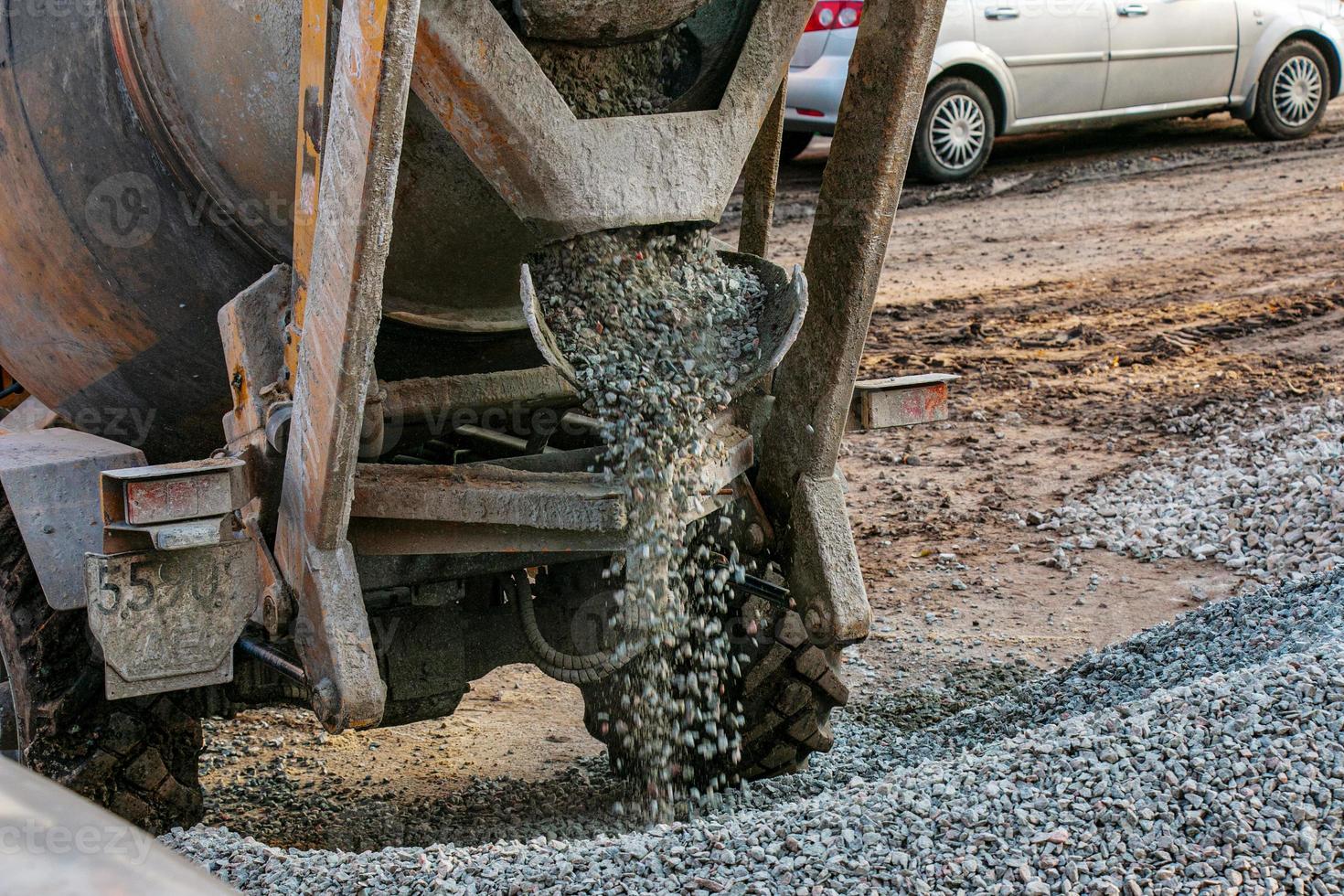 Mobile concrete mixer at the construction site. Close-up of gravel being loaded into a concrete making machine photo