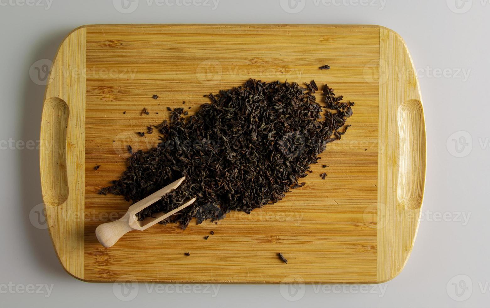 Dry black tea with bergamot flavor Gray graph as background, top view. A handful of tea on a wooden kitchen board. photo