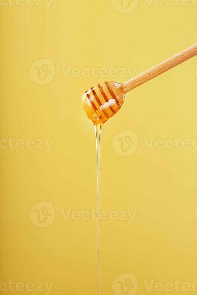 Natural Honey flows down from a honey bucket on a yellow background
