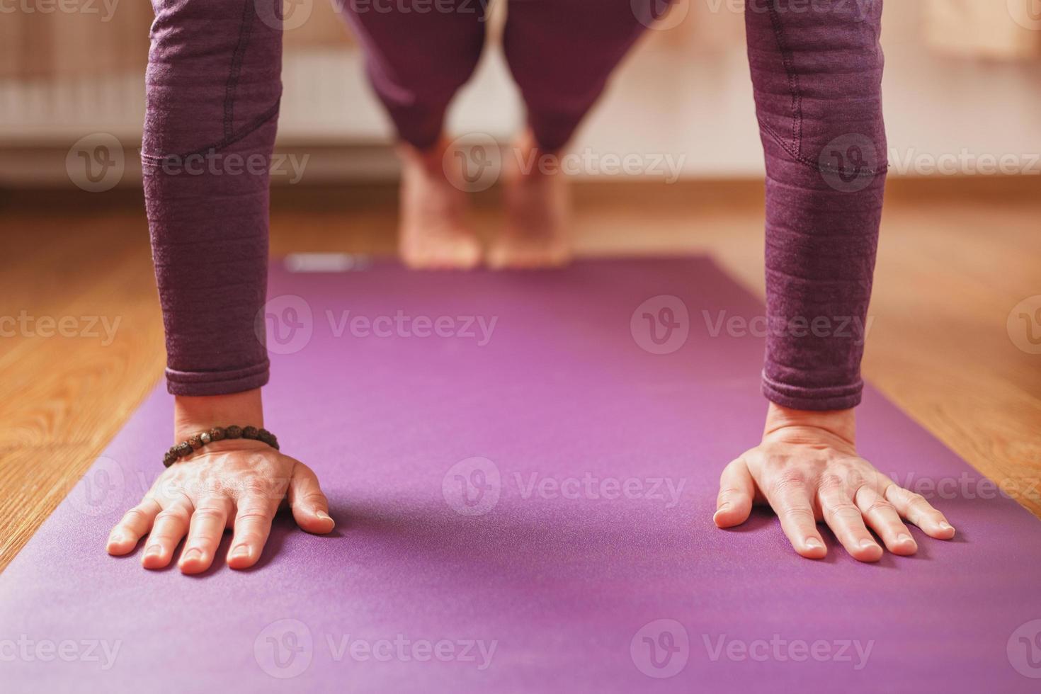 una chica hace asanas de yoga en una alfombra lila en la sala de estar foto