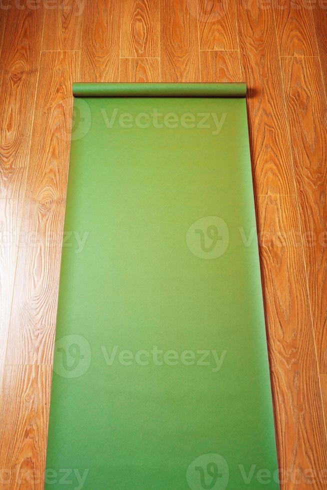 Green Yoga mat on wooden floor unfolded. Healthy lifestyle, fitness, sports. photo