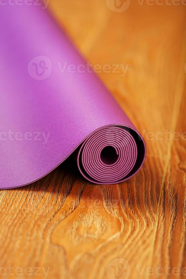 colchoneta de yoga y fitness púrpura sobre suelo de madera foto