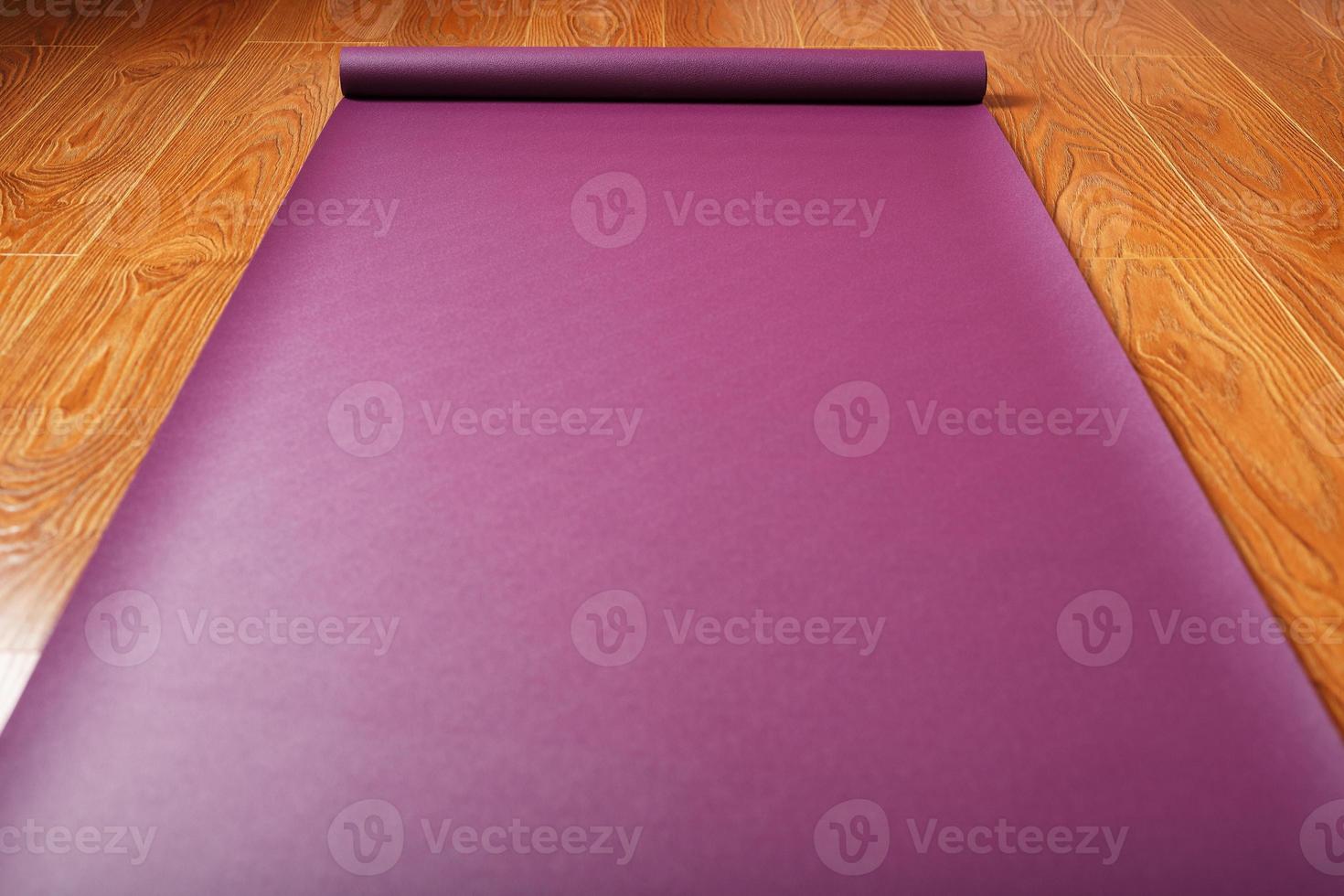 A lilac-colored yoga mat is spread out on the wooden floor with a Ganapati figurine photo