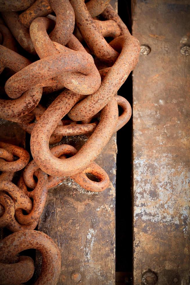 Old rusty chain on wooden background photo