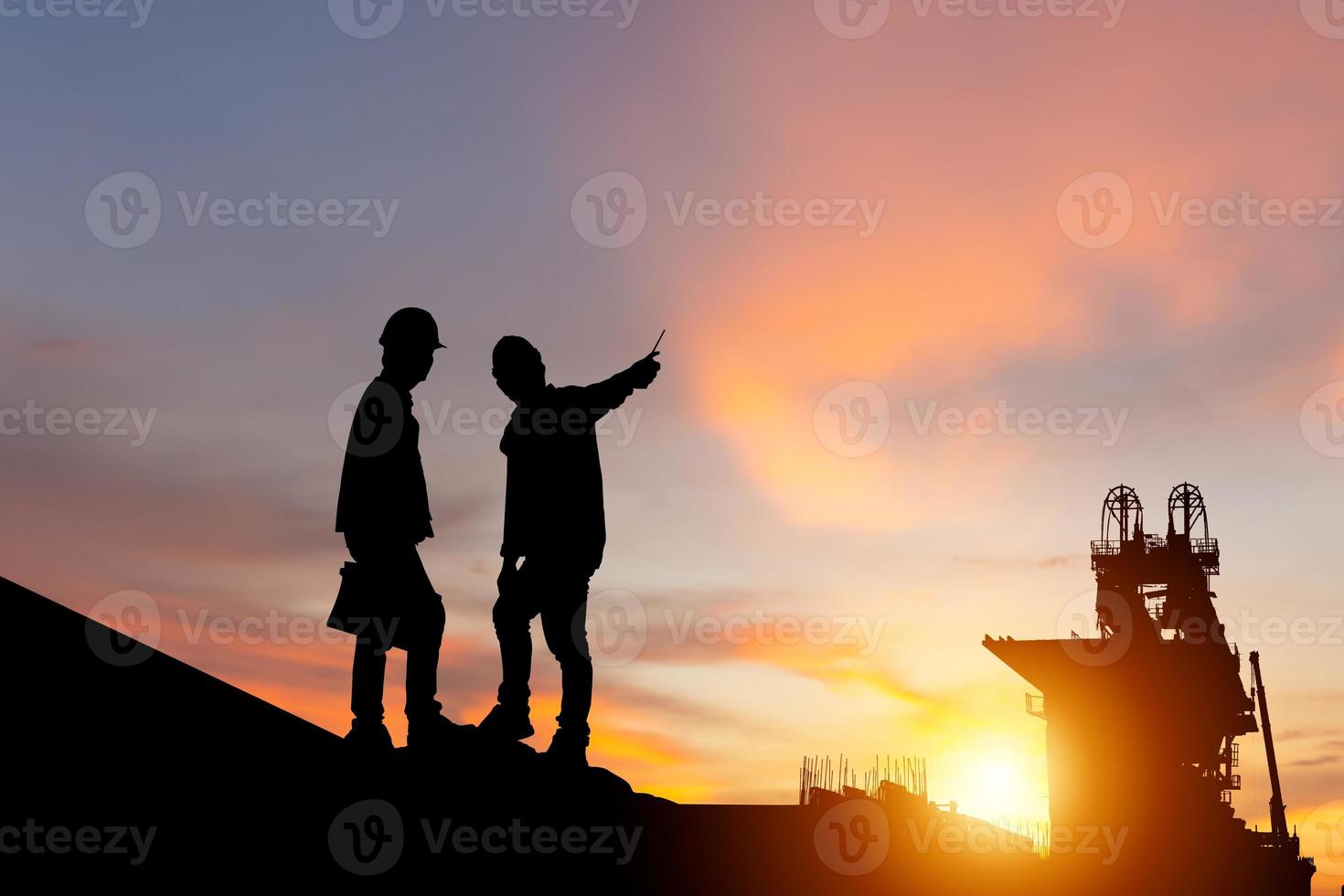 Silhouette of Engineer and worker man checking project at building site background, Infrastructure construction site at sunset in evening time photo