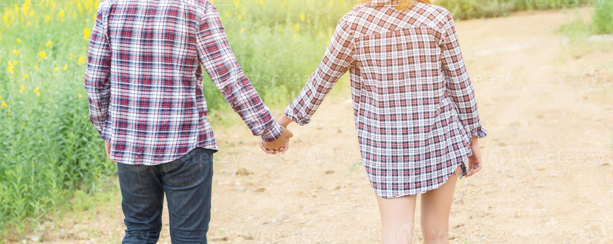 Young hipster couple relaxing in yellow flower field at summer. Enjoying with nature. photo