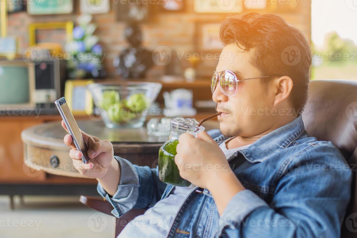 Young man with smartphone smiling relaxing at cafe. photo