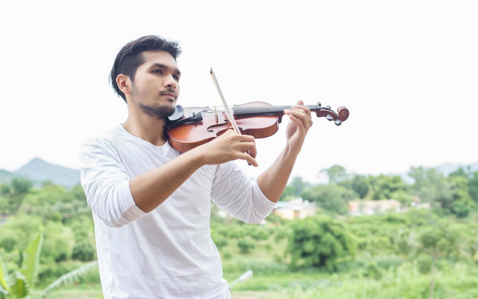 Young hipster musician man playing violin in the nature outdoor lifestyle behind mountain. photo