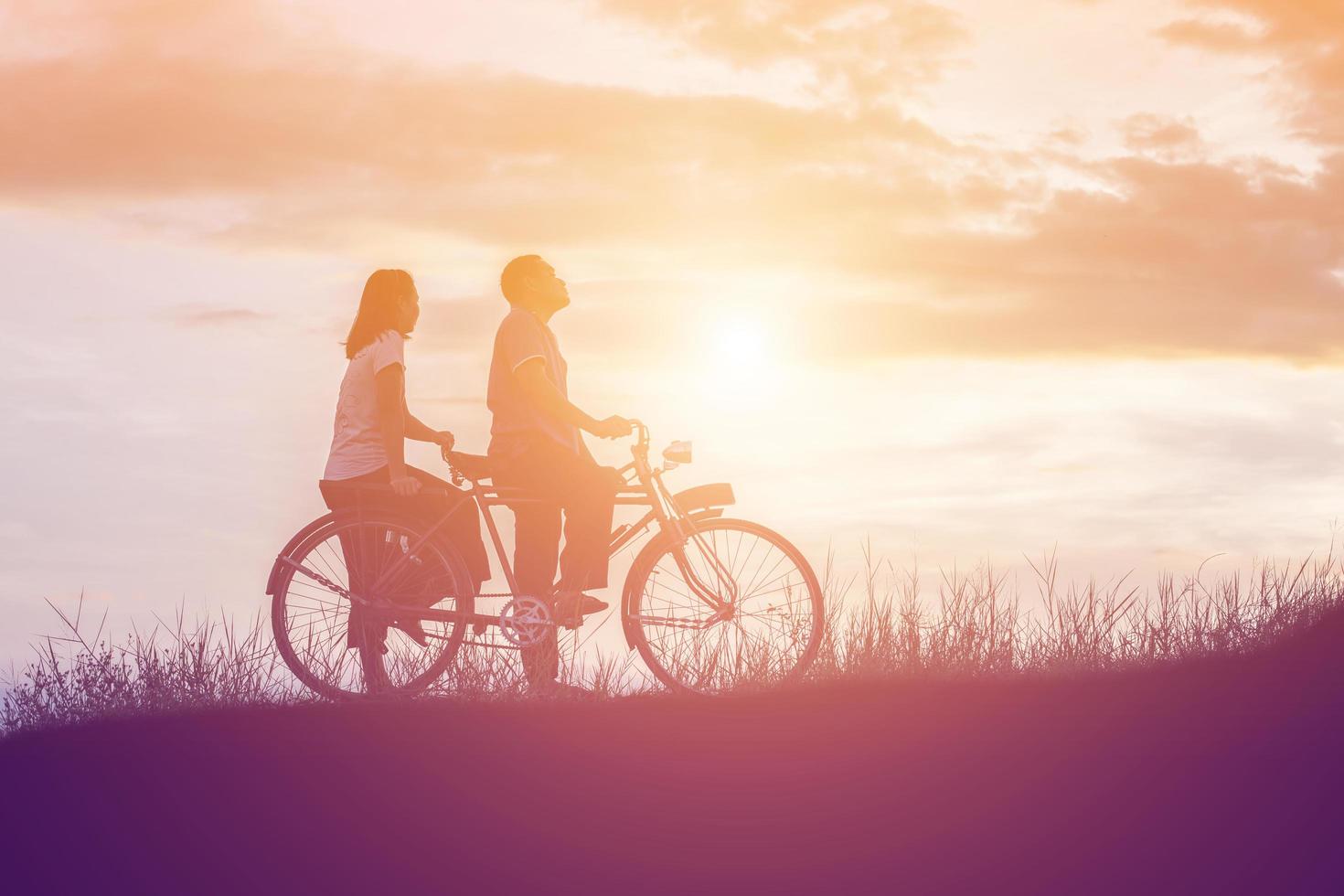 silhouette of sweet young couple in love happy time on bicycle photo