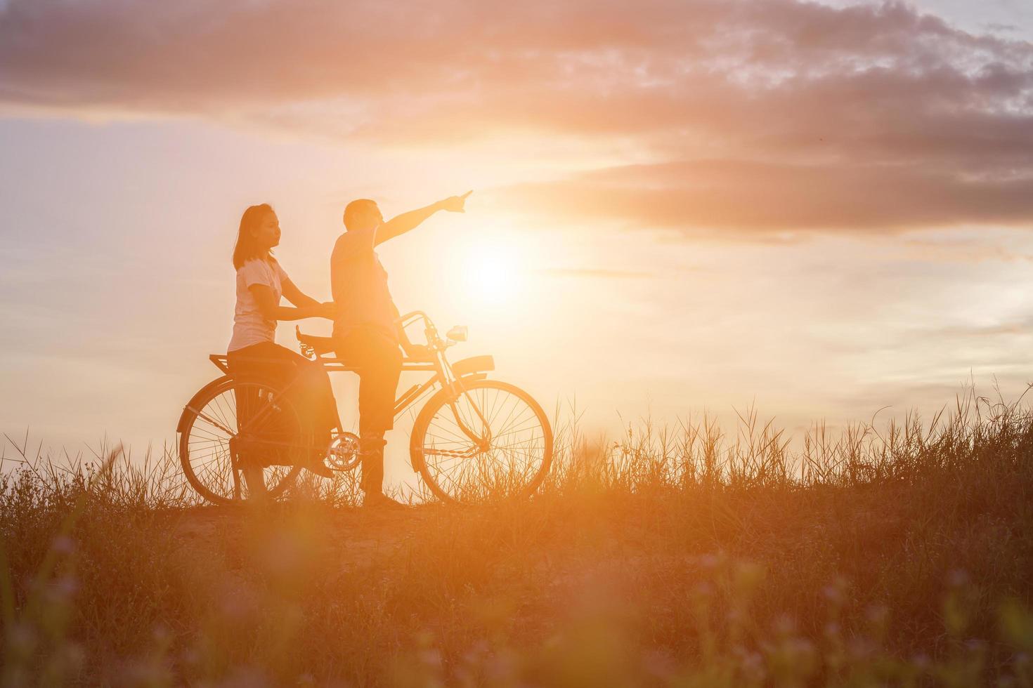 silhouette of sweet young couple in love happy time on bicycle photo