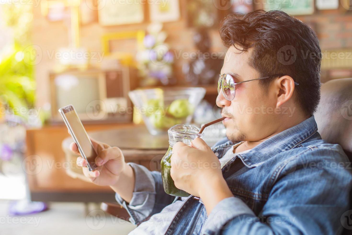 Young man with smartphone smiling relaxing at cafe. photo