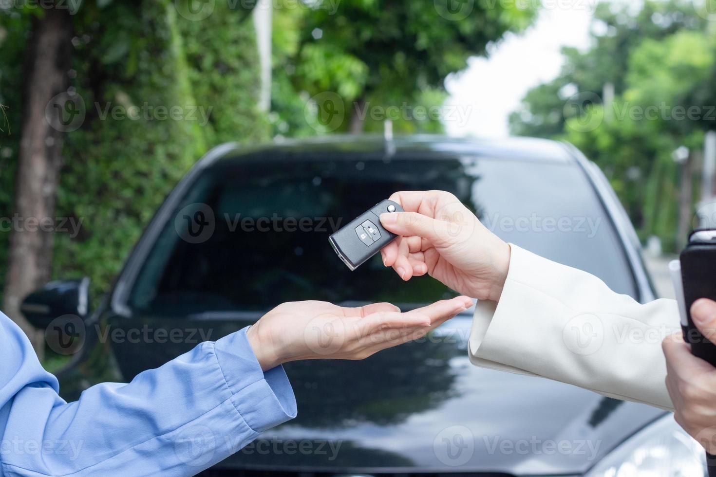 Beautiful young woman holding car keys and handing to Asian female customer. photo