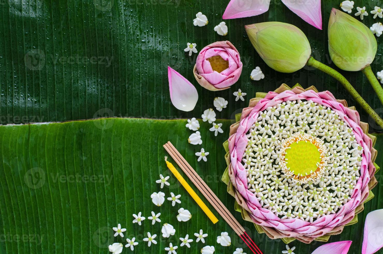 el krathong de pétalos de loto rosa decora con su polen, flor de corona, palo de incienso y vela para la luna llena de tailandia o el festival loy krathong sobre fondo de hojas de plátano. foto