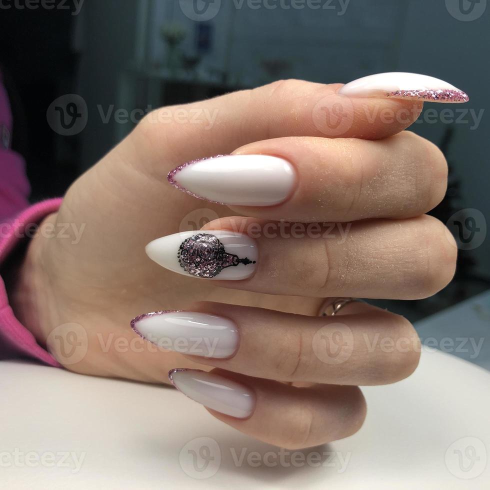 The hand of a young woman with a white manicure and design for the New Year and Christmas. photo