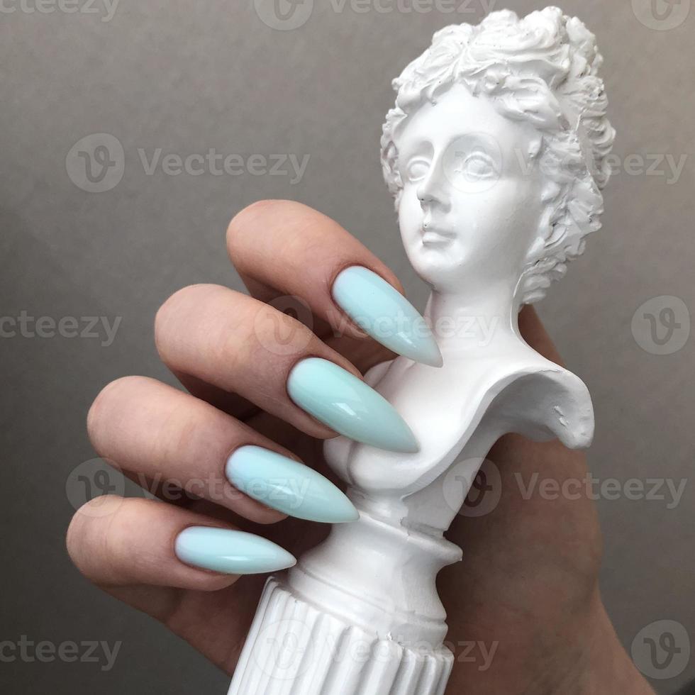 elegante manicura azul femenina de moda con diseño.manos de una mujer con manicura azul en las uñas foto