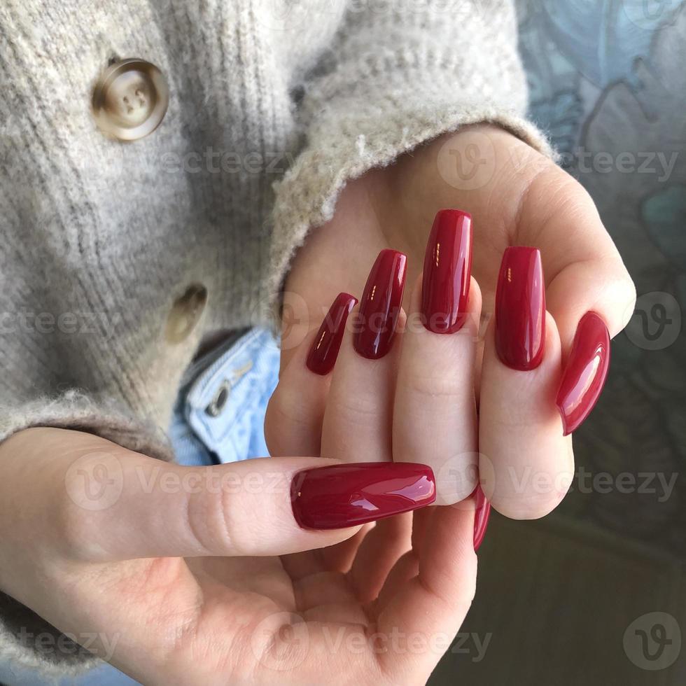 elegante manicura femenina roja de moda. manos de una mujer con manicura roja en las uñas foto