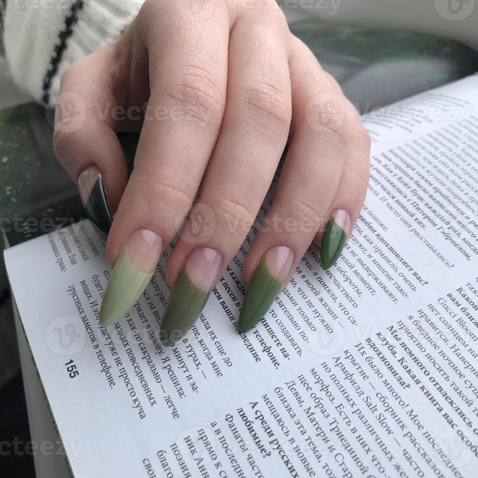 elegante manicura femenina verde de moda. manos de una mujer con manicura verde en las uñas foto