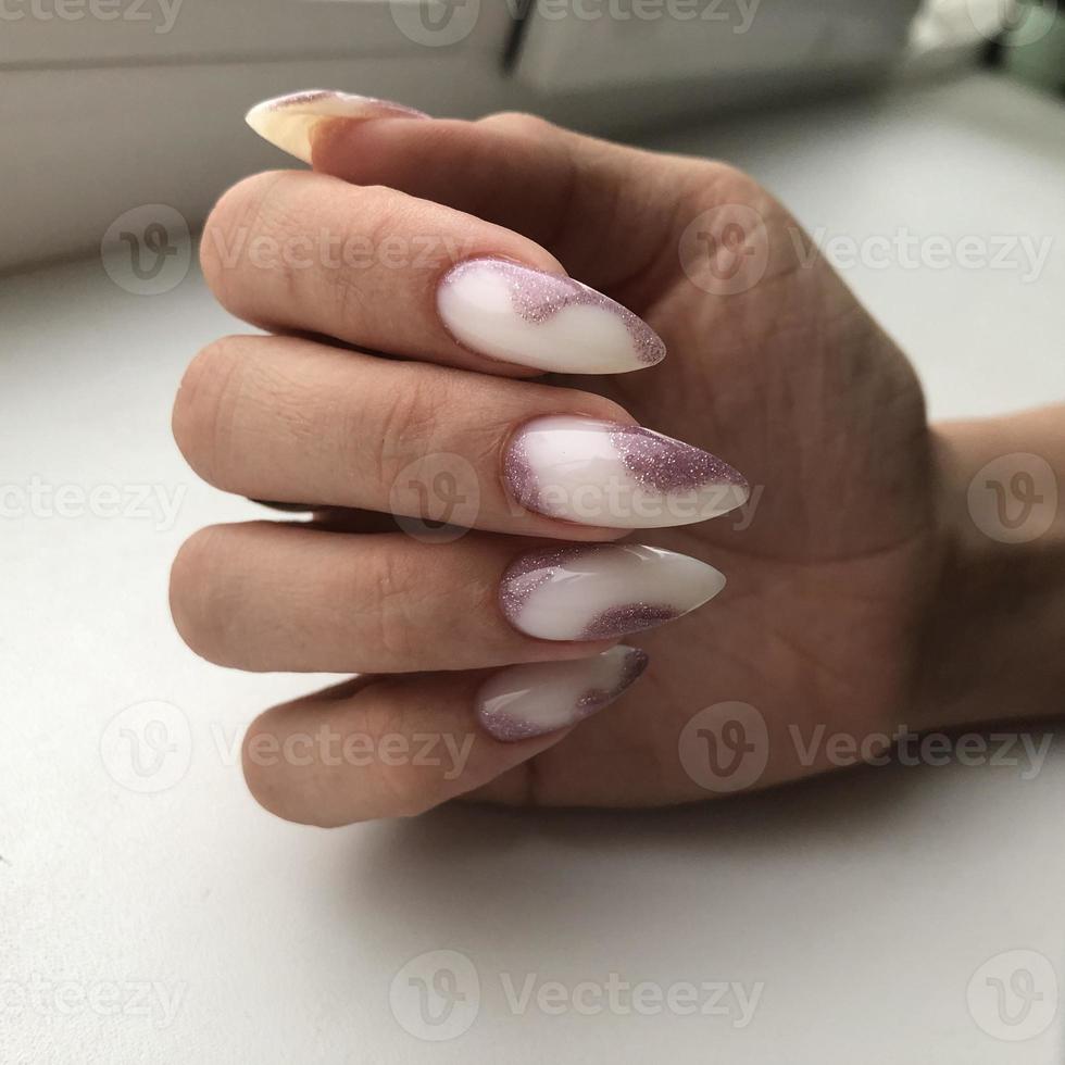 Stylish trendy female white manicure with design.Hands of a woman with white manicure on nails photo