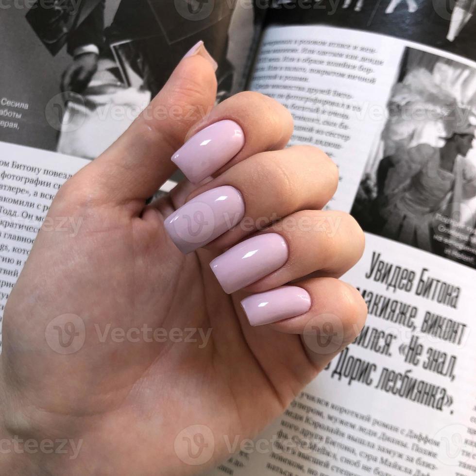 elegante manicura rosa femenina de moda. manos de una mujer con manicura rosa en las uñas foto