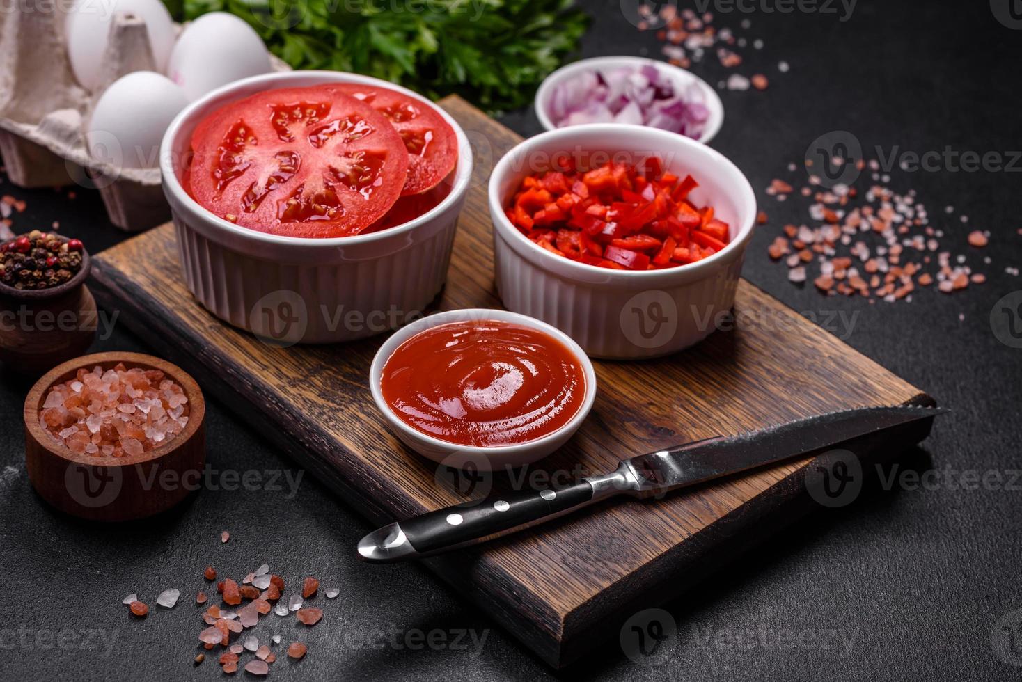 Ingredients for making shakshuka, dishes with fried eggs with tomato sauce, spices and herbs photo