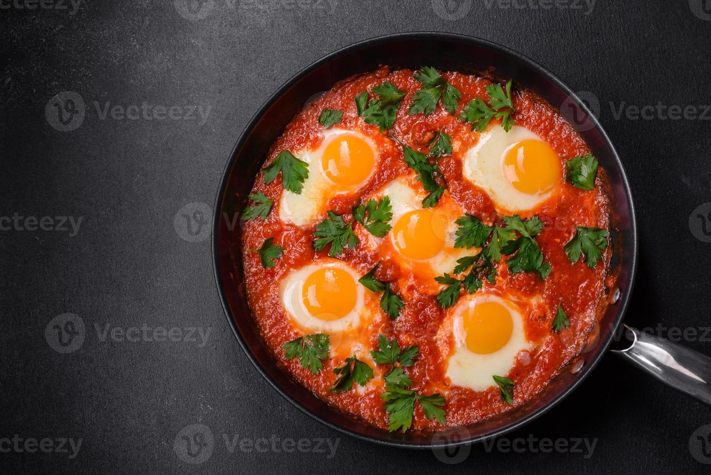 Shakshuka, a dish with fried eggs with tomato sauce, sweet pepper, garlic, onions, spices and herbs photo