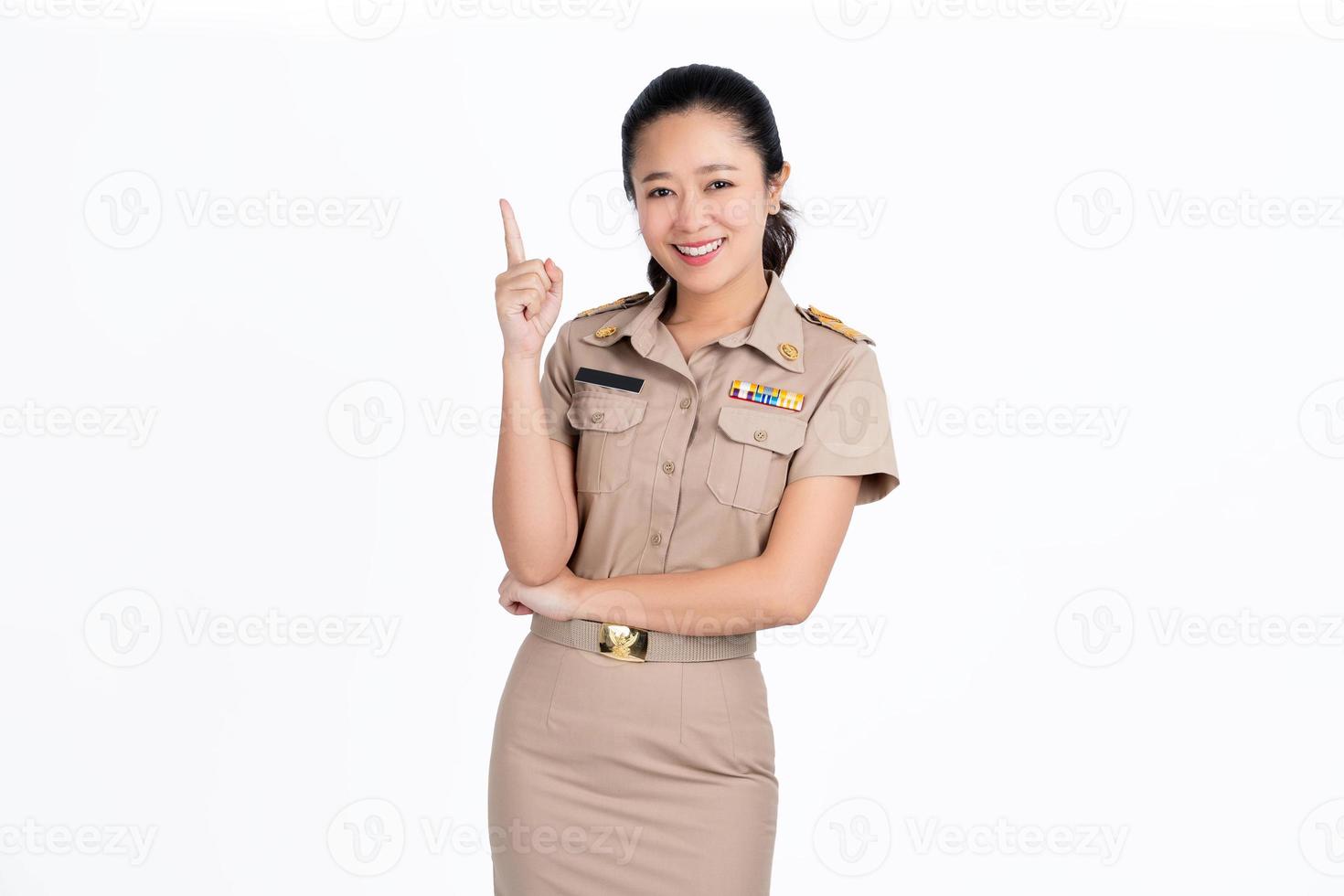 Hermosa profesora asiática apuntando al espacio de copia vacío aislado en fondo verde. foto